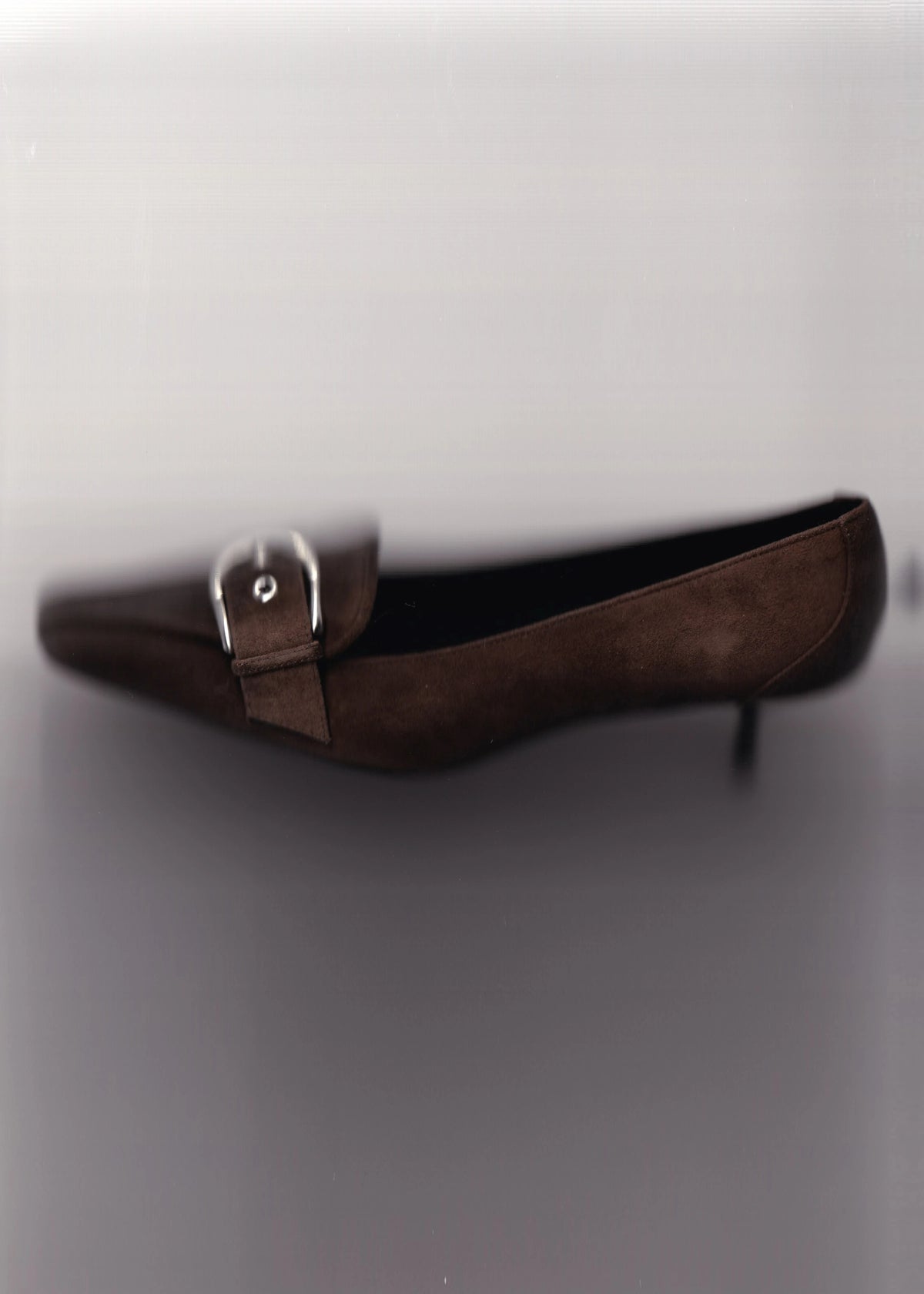Brown buckle flat against a soft gray background.