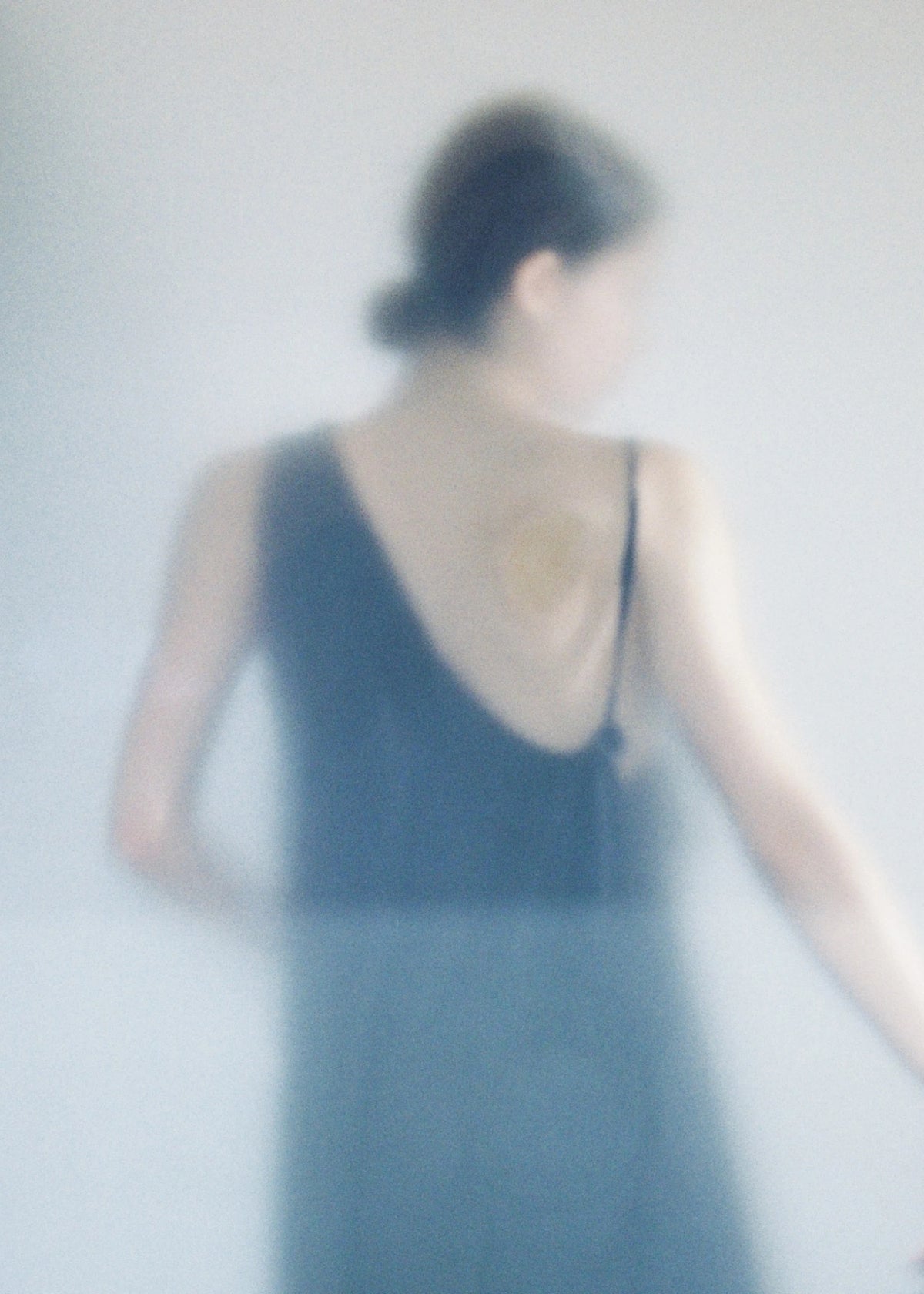 Soft-focus back view of a model in a black dress.