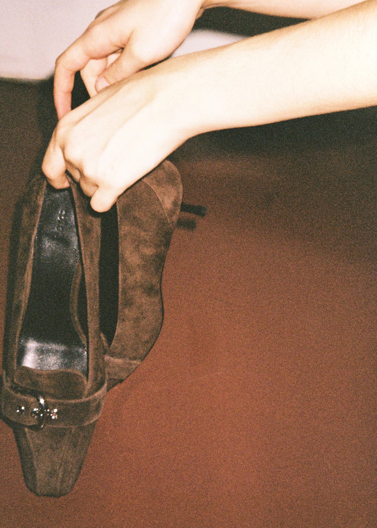 Hands holding a pair of dark shoes.