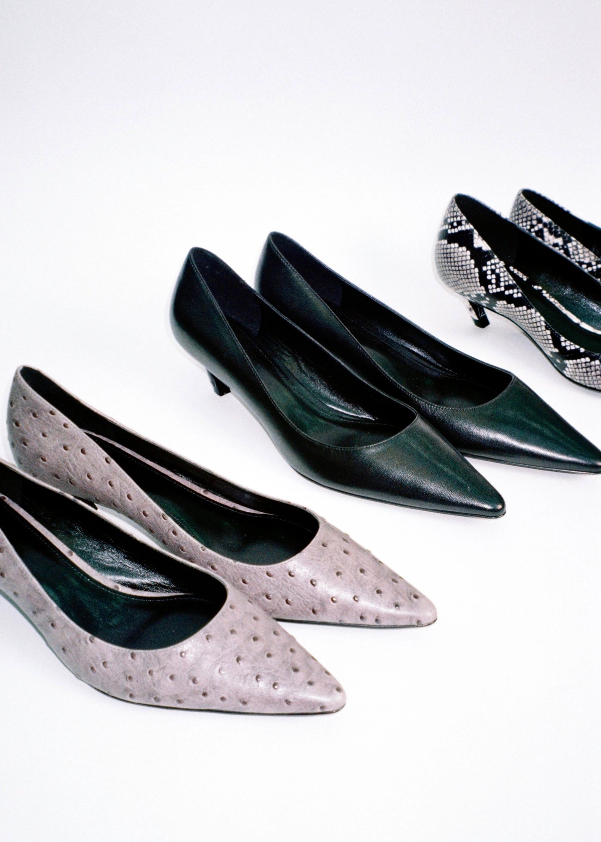 Black and pink pointed-toe pumps arranged on a pale background.